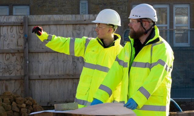2 drainage workers reviewing drainage plans before completing works